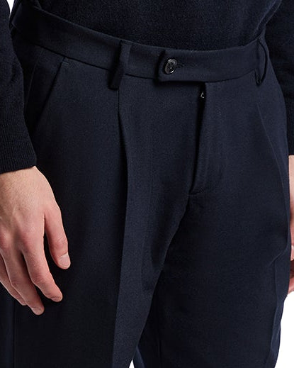 Navy pleated trousers in soft fabric, featuring a tailored fit and a classic button closure for stylish comfort.