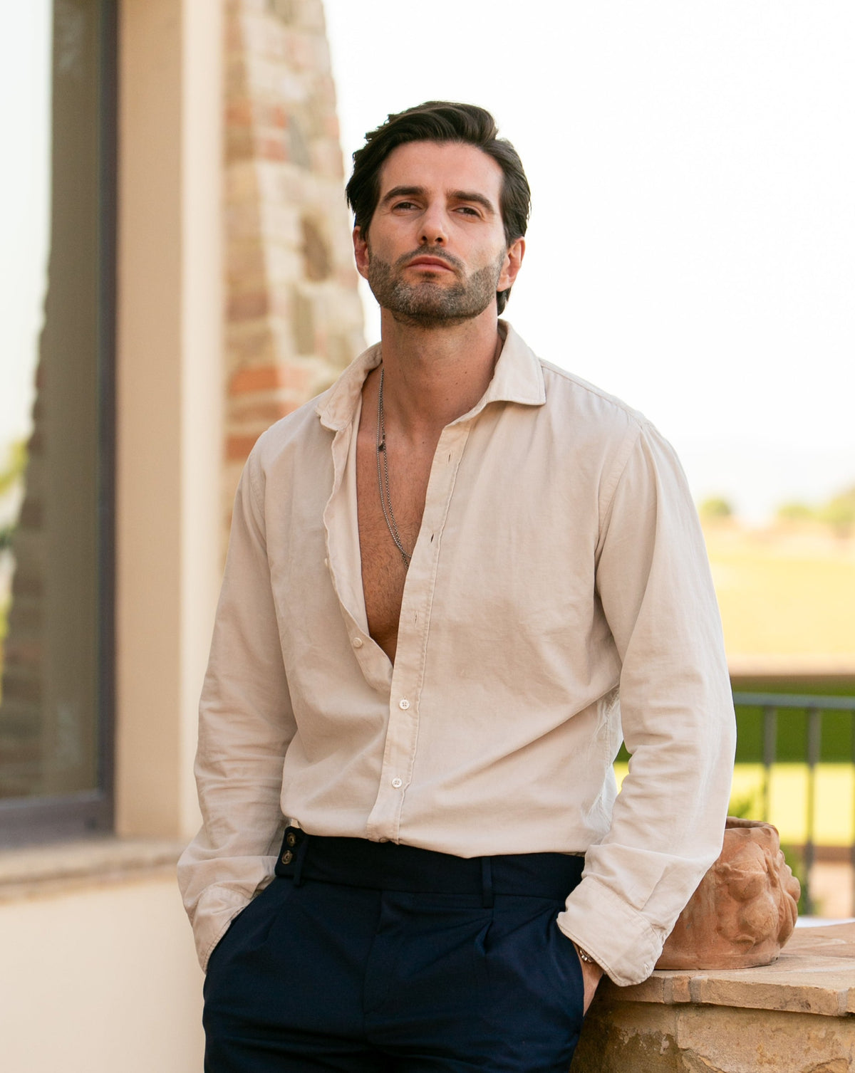 Men's cream linen button-down shirt with relaxed fit, paired with navy trousers for casual elegance.