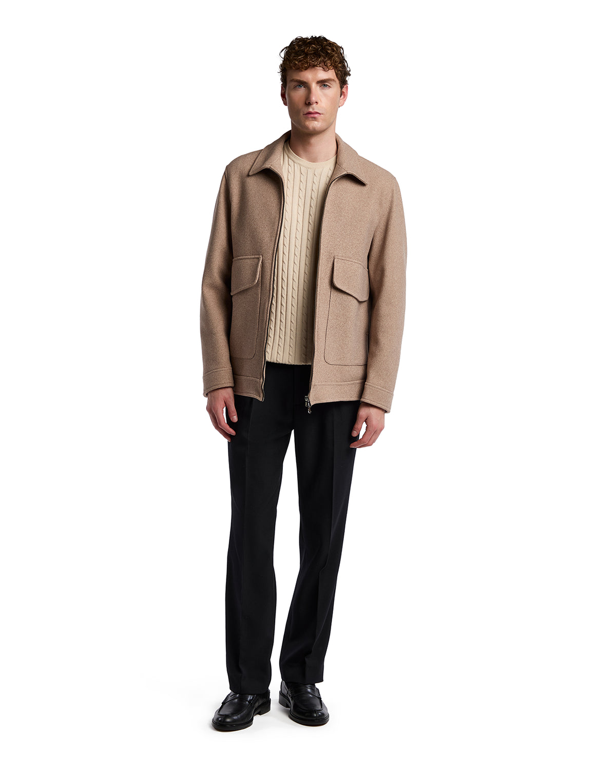 Men's beige wool blend jacket with pockets, paired with a cream cable-knit sweater and black trousers. Stylish and casual.