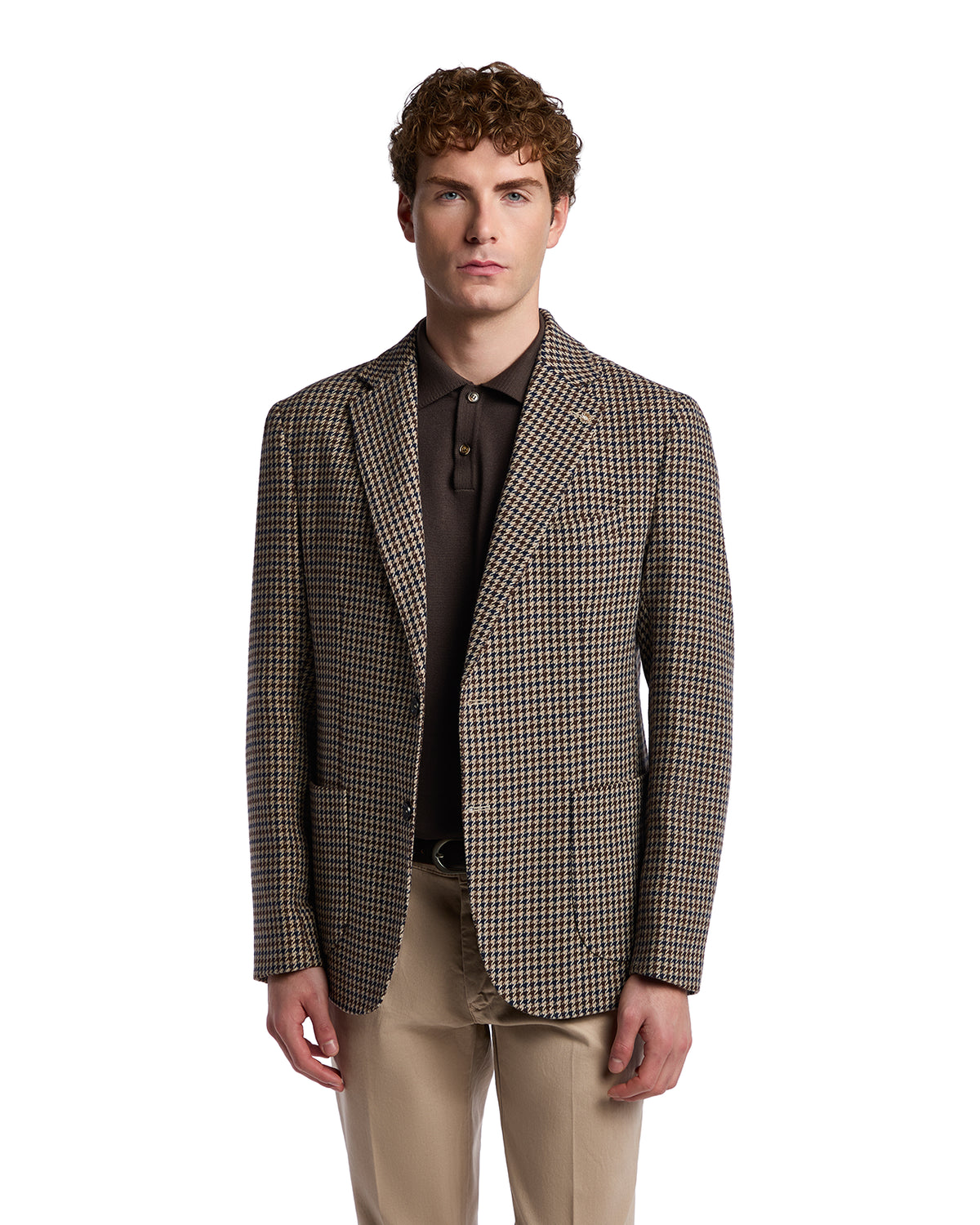 Men's brown houndstooth blazer in wool with two pockets, styled with a dark polo shirt and beige trousers.