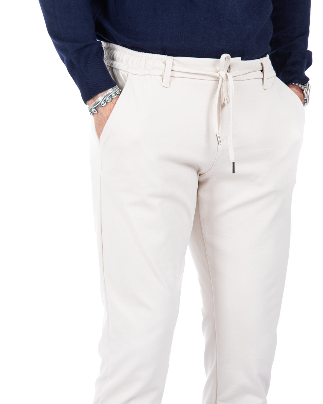 Men's cream tapered joggers with adjustable drawstring, paired with a navy sweater, perfect for casual wear.