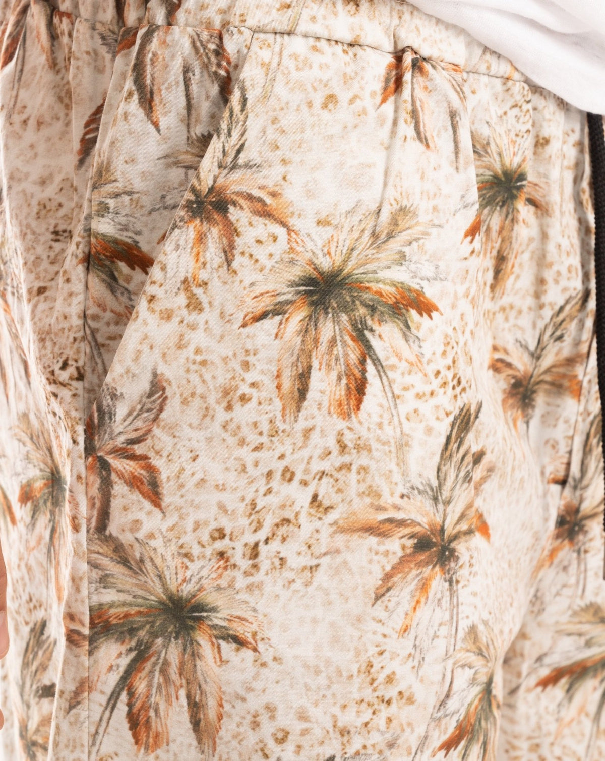 Close-up of beige shorts with a vintage palm tree print and side pocket