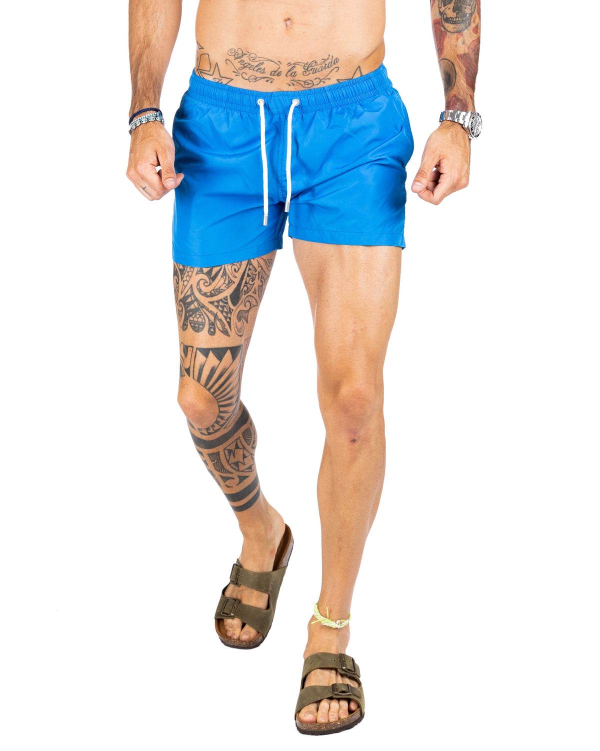 Men's bright blue swim shorts with elastic drawstring waist, shown on a model walking