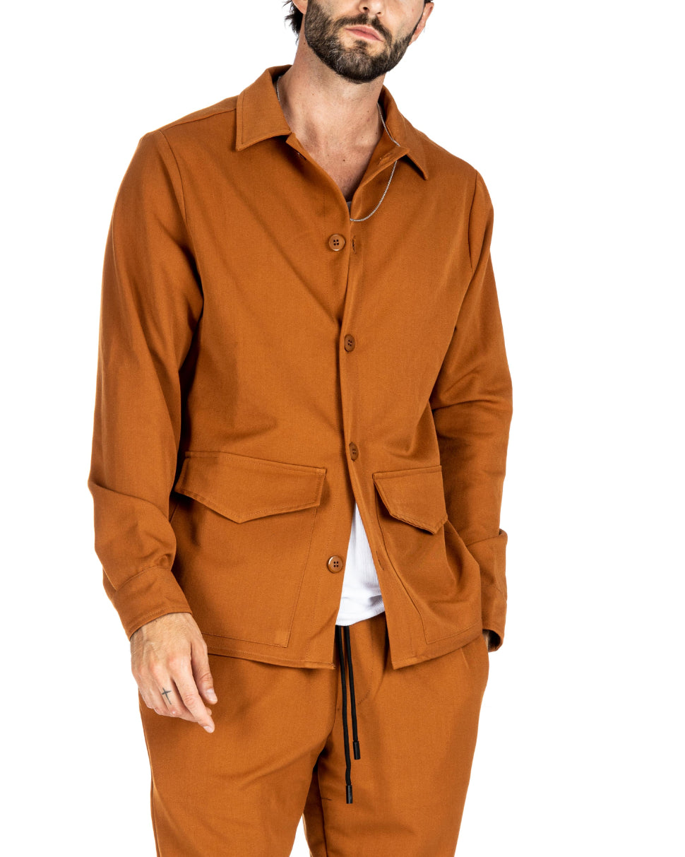Men's rust orange overshirt jacket with button front and pointed patch pockets, shown on a model with hands in pockets