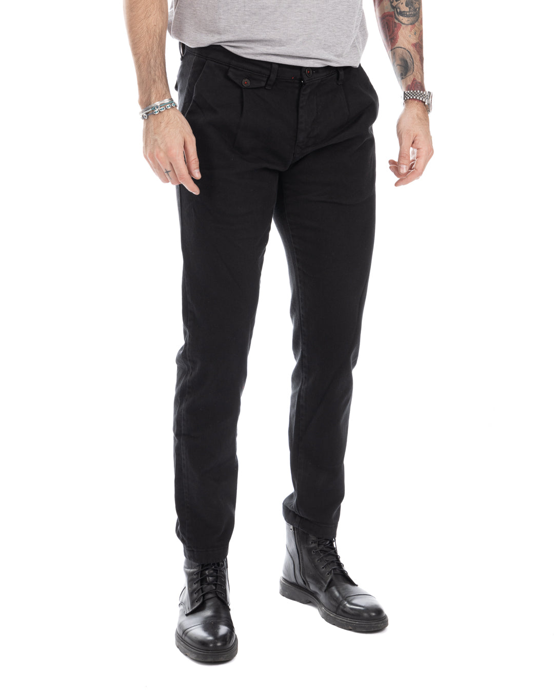 Men's black slim-fit cotton chinos with pleated front, paired with black leather combat boots.