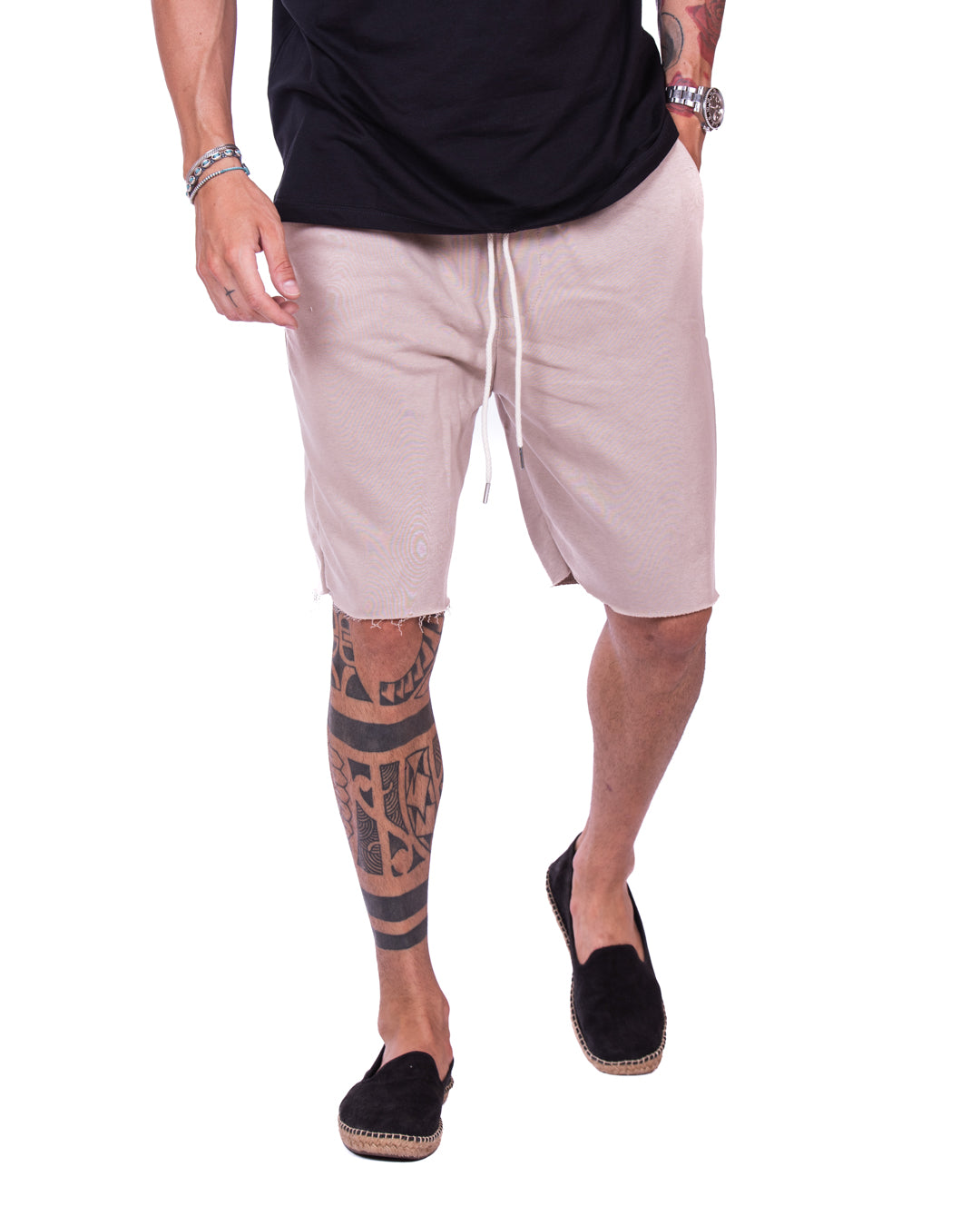 Men's beige cut-off sweat shorts with drawstring waist, shown mid-stride on a model with black espadrilles