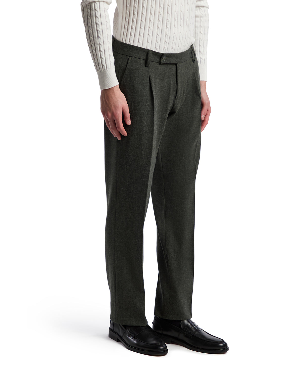 Men's tailored dark green wool trousers with pleats, paired with a cream cable knit sweater and black leather shoes.