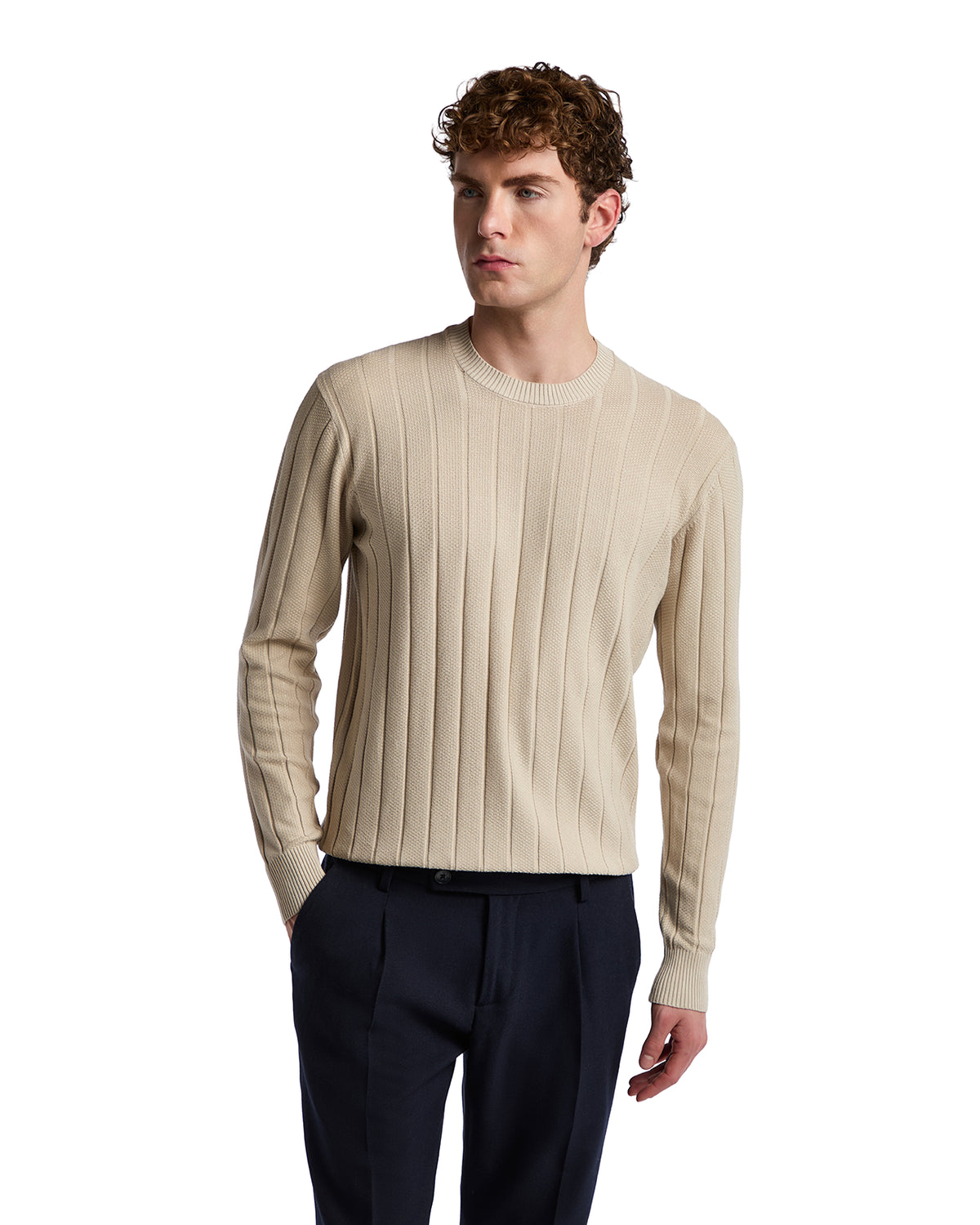 Beige ribbed knit sweater for men, featuring a crew neckline and long sleeves, paired with navy trousers.