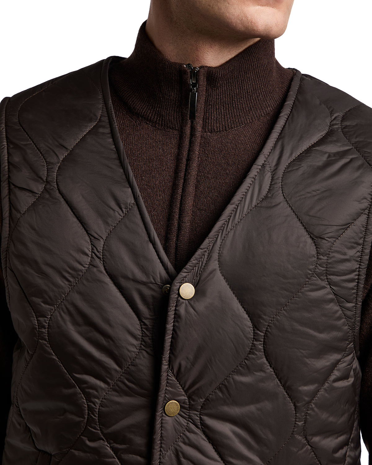 Brown quilted vest with gold buttons over a dark brown zip-up sweater, offering a stylish layered look for colder weather.