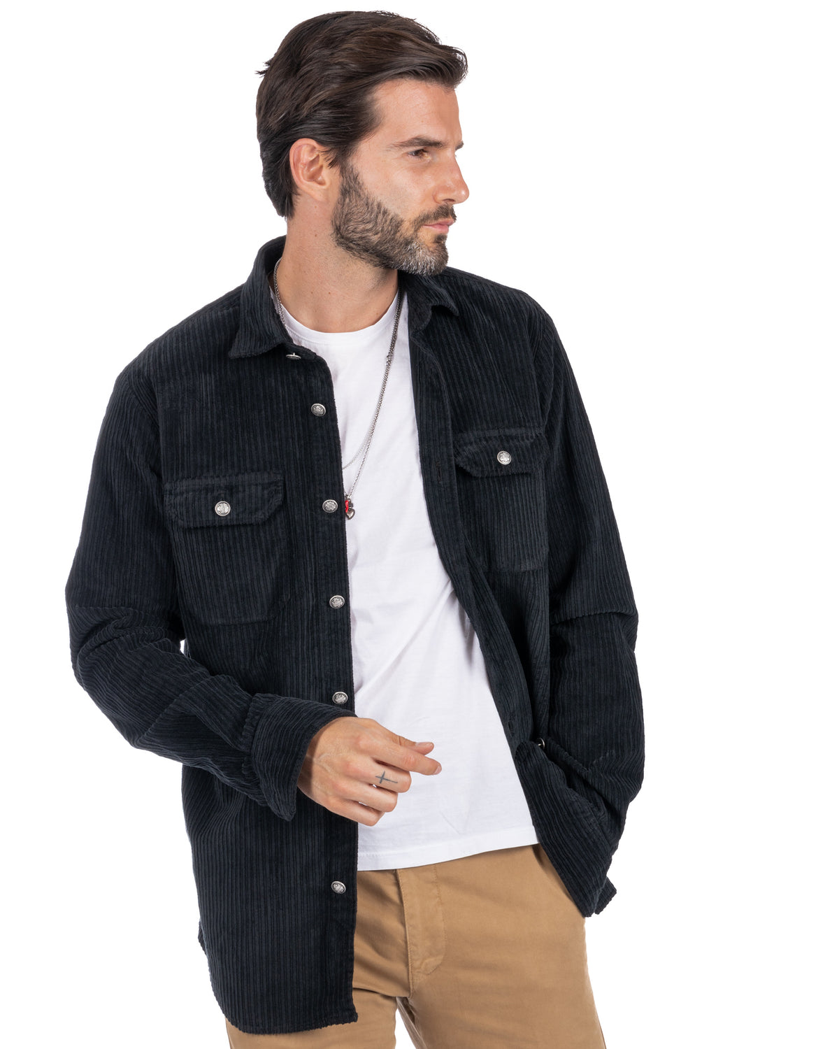Men's black corduroy button-up shirt jacket with silver snap buttons, chest pockets, worn over white tee and tan pants.