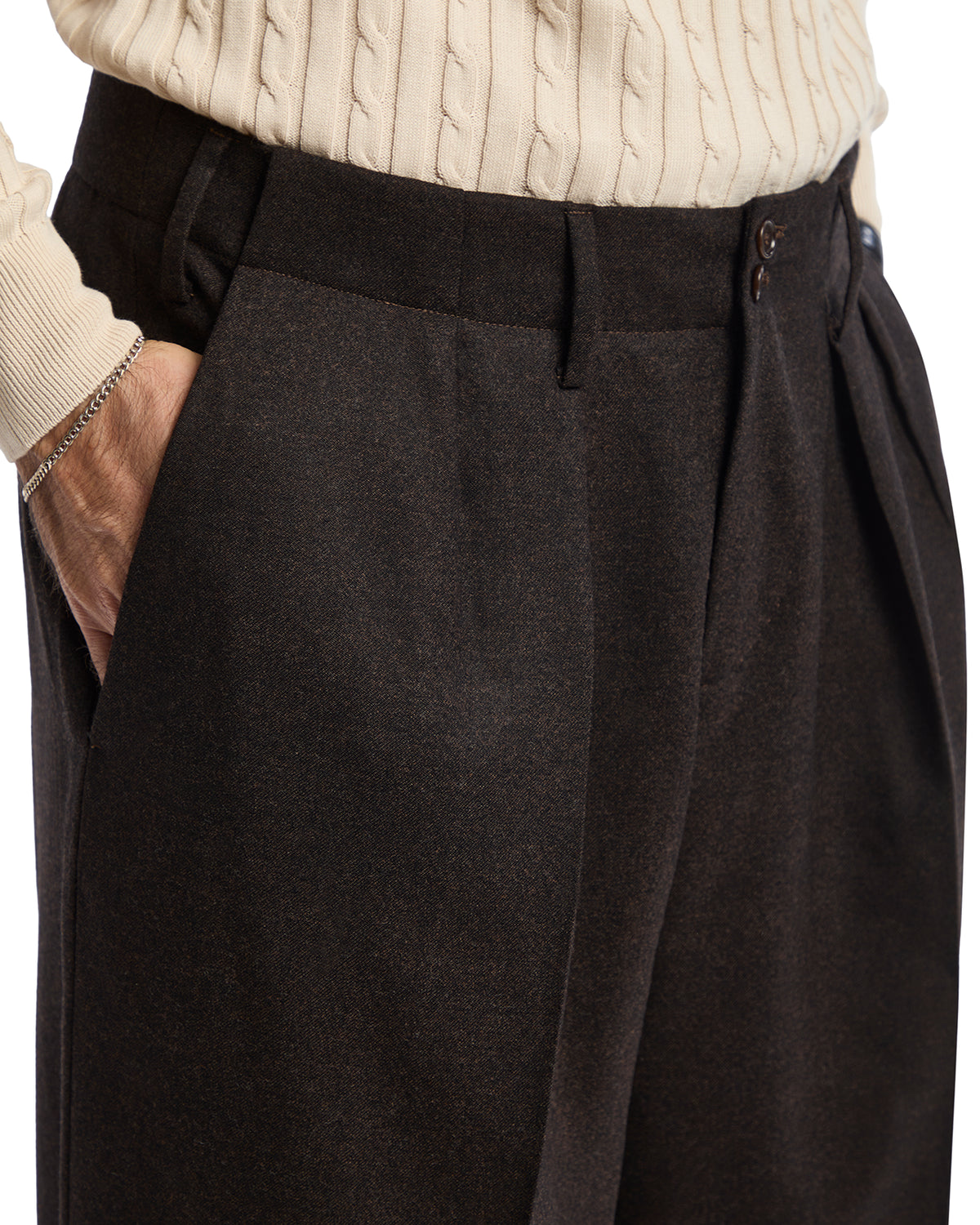 Men's brown pleated wool pants styled with a cable knit creamy sweater, featuring side pockets and a tailored fit.