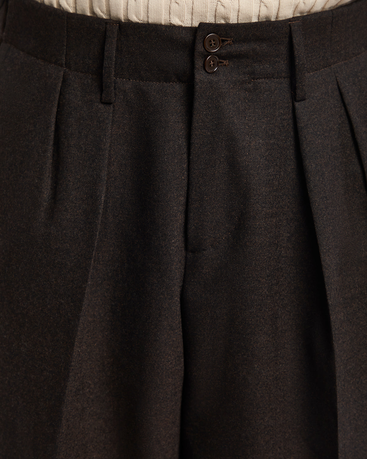 Dark brown pleated trousers with a tailored fit, featuring two-button closure and a textured waistband.