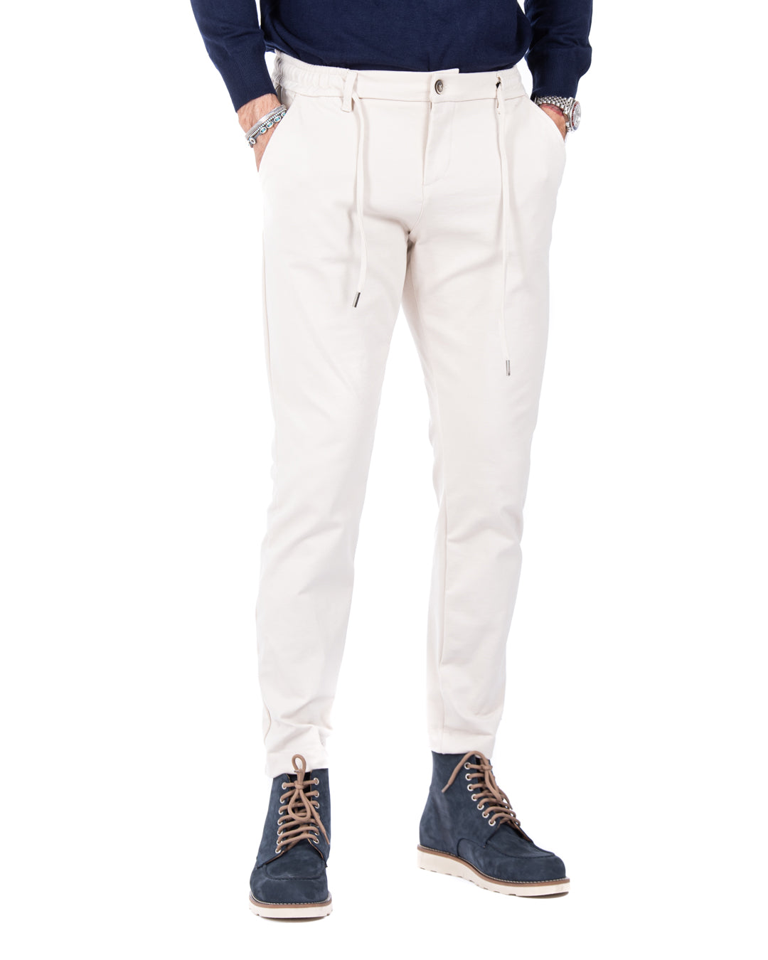 Men's cream drawstring pants in lightweight fabric, paired with navy suede boots for a stylish, casual look.