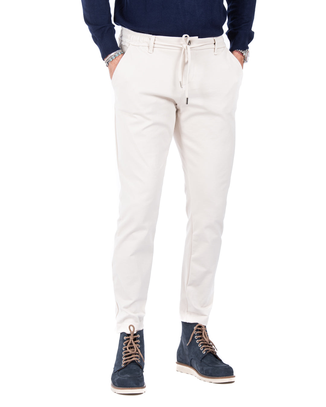 Men's cream jogger pants in stretchy cotton, styled with an elastic waistband and paired with navy suede boots.