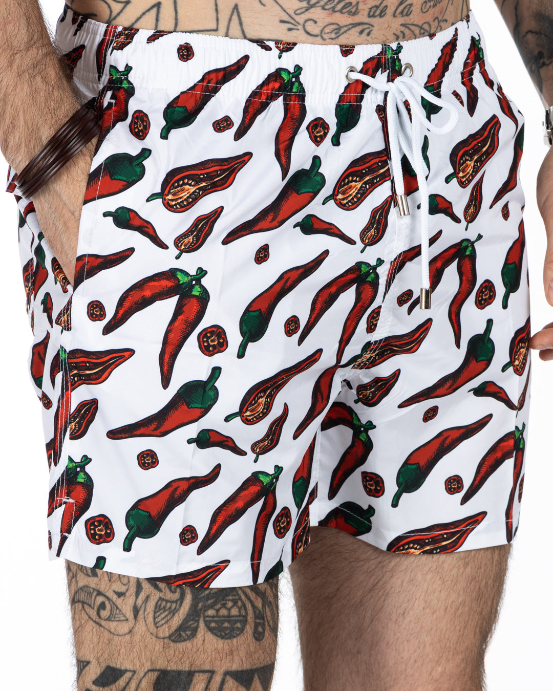 White men's swim trunks with red chili pepper print, drawstring waist, and side pockets. Quick-dry beach shorts.