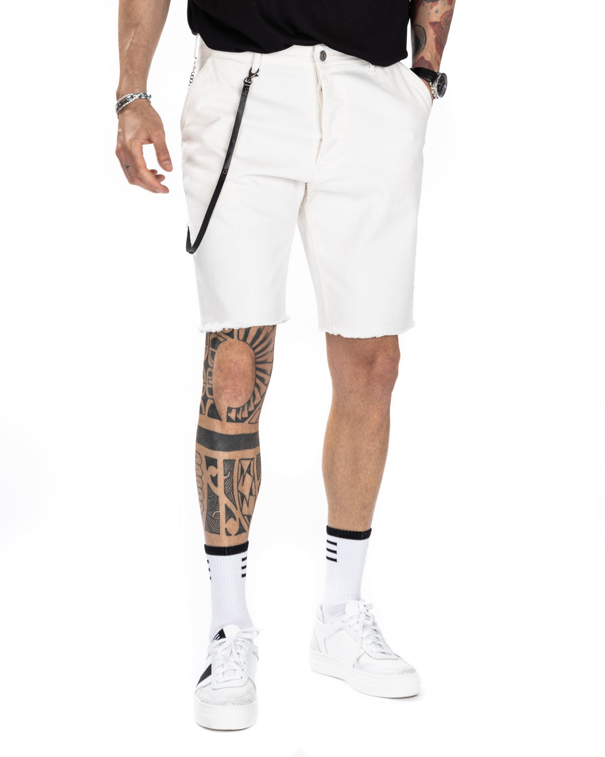 Men's off-white denim Bermuda shorts with frayed hem and black leather keychain detail, shown on a model