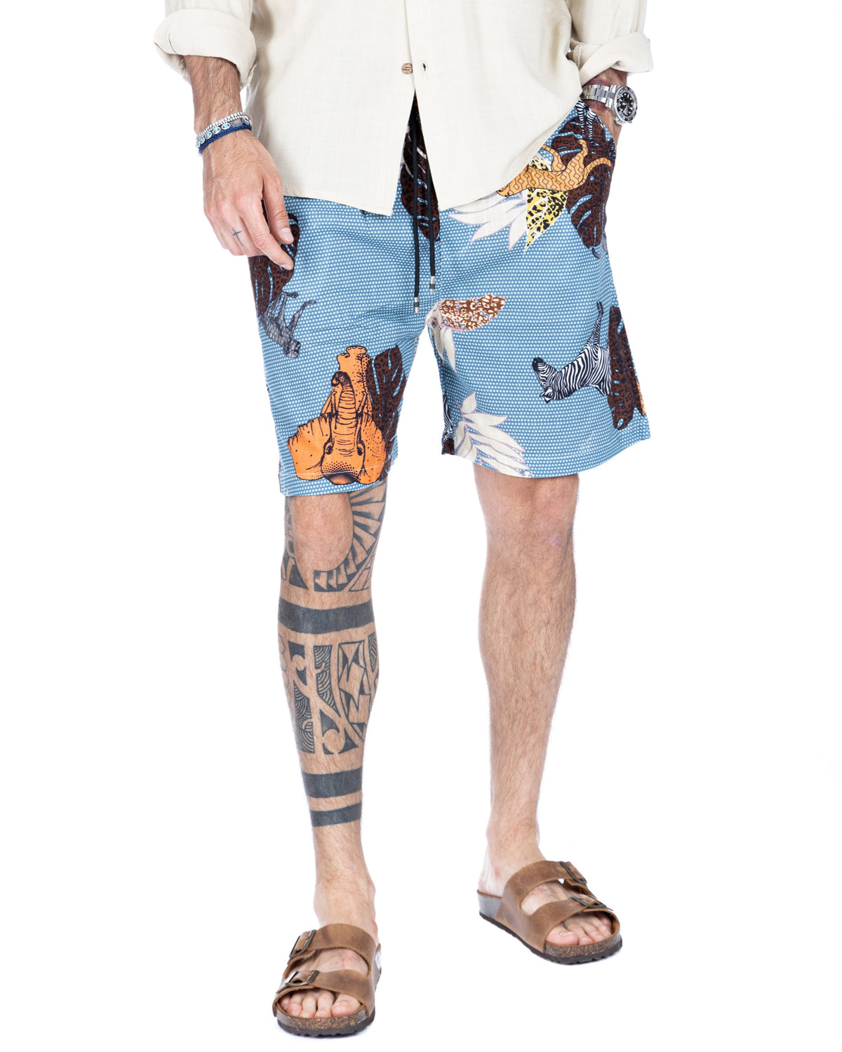 Men's light blue safari print drawstring shorts with animal motifs, shown on a model in full stance
