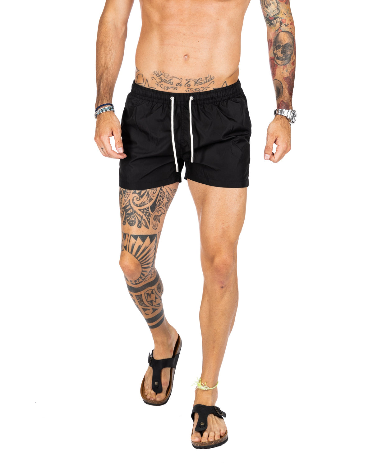 Men's plain black swim shorts with white drawstring cord, shown on a model walking