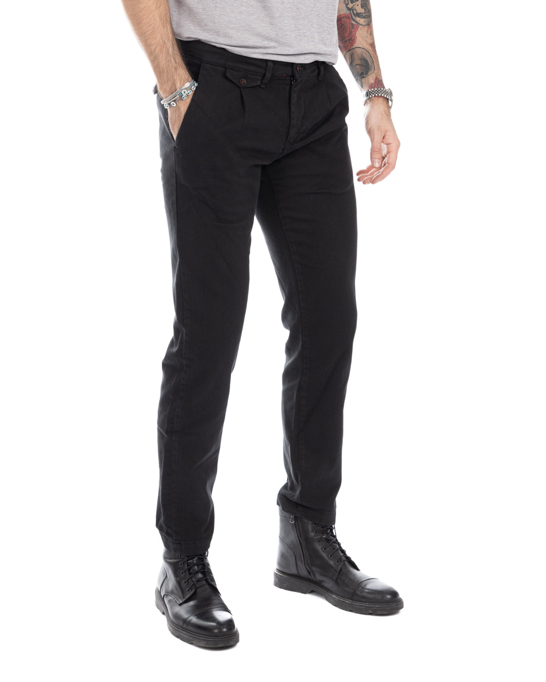 Men's black slim-fit cotton chinos with pleated front, paired with leather combat boots. Casual tailored trousers.