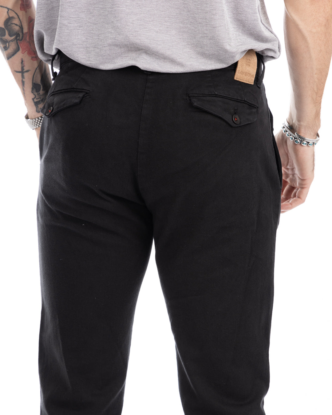 Black slim-fit chino pants with button-back pockets, leather brand patch, and tailored waistband.