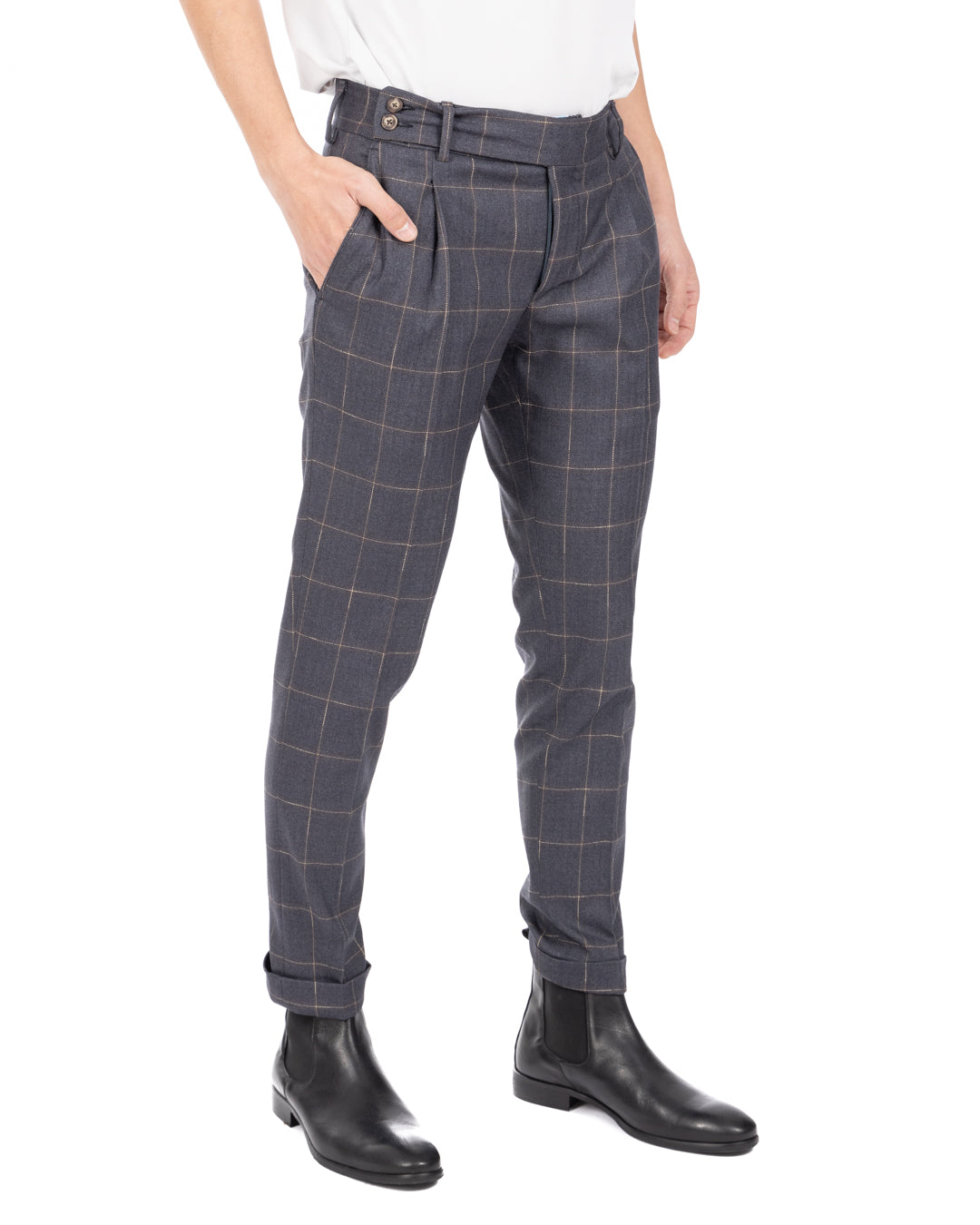 Men's blue-gray windowpane check pleated wool trousers worn with hand in pocket, black Chelsea boots, front view
